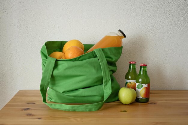 Photo sac réutilisable avec de la nourriture sur la table, des fruits et du jus dans une bouteille en verre, consommation écologique