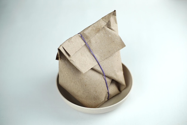 Photo un sac de riz enveloppé de papier brun dans un bol avec un élastique violet