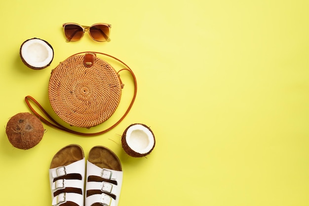 Sac rond en rotin noix de coco birkenstocks branches de palmier lunettes de soleil sur fond jaune bannière vue de dessus avec espace de copie sac et chaussures en bambou à la mode mode d'été mise à plat concept de vacances de voyage