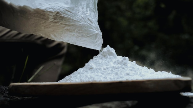 Un sac de sable blanc est versé dans un sac.