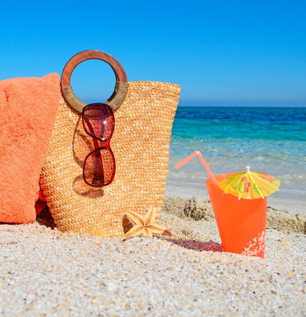 Sac serviette et boisson sur le sable