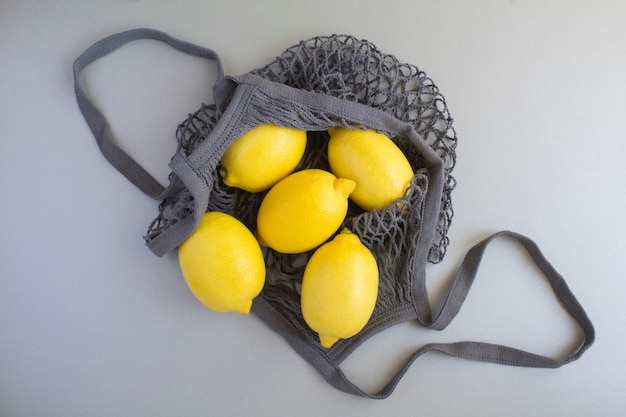 Sac shopping en maille gris avec citron sur fond gris. Pas de concept de sac en plastique. Gros plan.Vue de dessus.