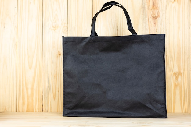 Photo sac shopping noir ou sac noir sur table en bois.