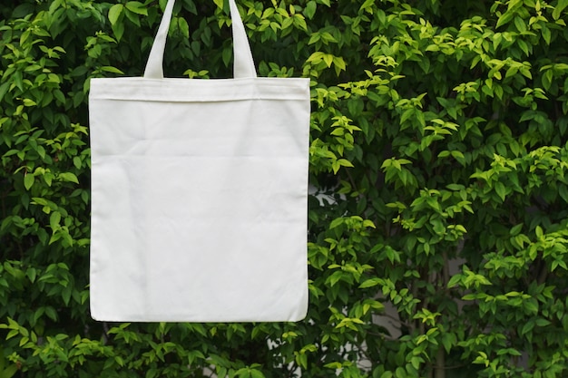 Sac en tissu blanc suspendu à une feuille verte