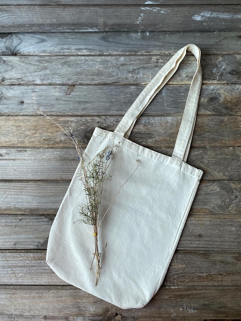 Photo sac en tissu avec un bouquet de plantes sur un fond en bois