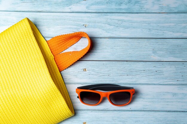 Un sac vide avec une poignée et des lunettes de soleil se trouvant sur un fond en bois bleu