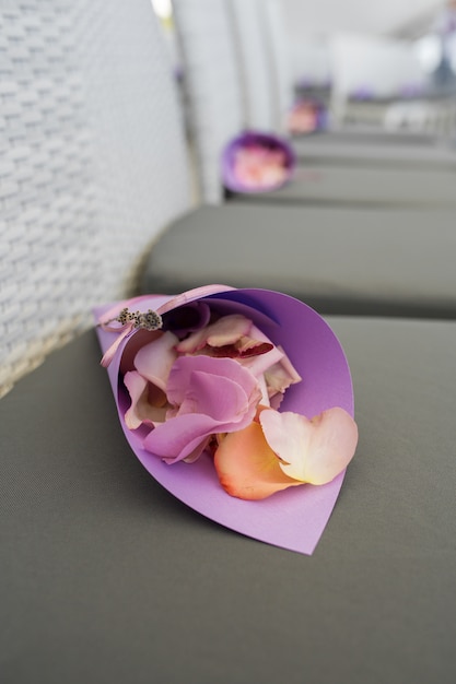 Un sac violet avec des pétales de roses à arroser sur les nouveaux mariés était posé sur la chaise