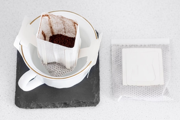 Un sachet de café filtre prêt à l'emploi ouvert dans une tasse