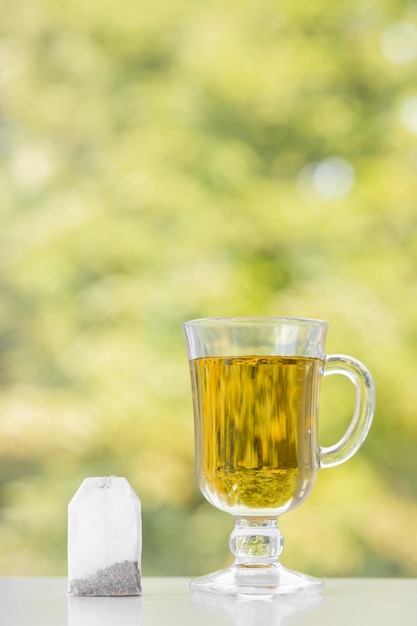 Sachet de thé et tasse de thé sur fond d'été vert