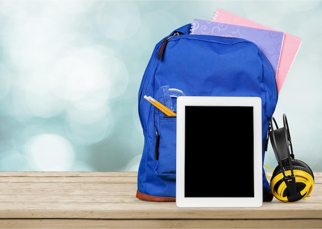 Sack scolaire bleu avec tablette et écouteurs en arrière-plan de la salle de classe