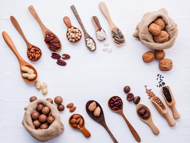 Photo sacs de chanvre et cuillère de diverses légumineuses et de différents types de noix noix noyaux noix de noisette noyaux d'amande noyaux de pinto rouge haricots et noix de pécan disposés sur une table en bois blanc