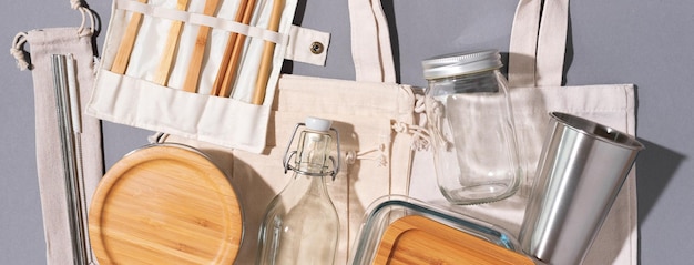 Sacs en coton bocal en verre bouteille tasse en métal pailles pour boire des couverts en bambou et des boîtes sur fond gris Mode de vie durable Concept de magasinage sans plastique zéro déchet
