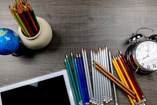 sacs, crayons, livres utilisés dans des classes placées sur un plancher de bois.