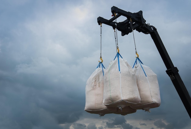 sacs avec des graines suspendues par une grue sur le fond du ciel