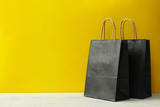 Sacs en papier sur table en bois contre jaune