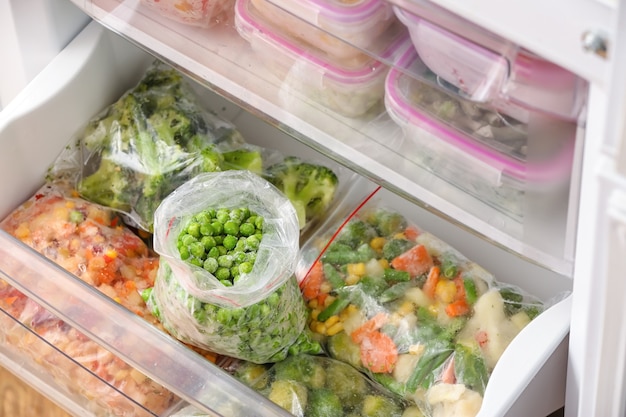 Sacs en plastique avec des pois verts surgelés et différents légumes au réfrigérateur