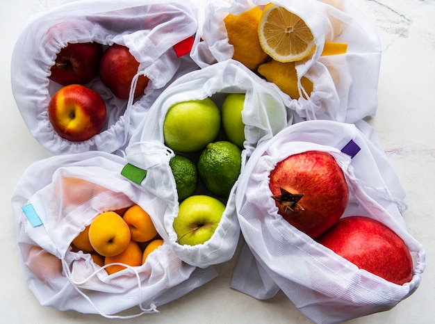 Sacs à provisions en filet avec des fruits biologiques sur une surface en marbre