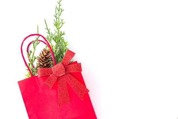 Sacs à provisions rouges et verts avec décoration de Noël, branches de sapin, arc festif isolé sur l'espace de copie de la vue de dessus de fond blanc. Concept de vente de Noël