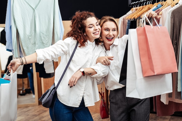 Sacs de vêtements. Joyeuse mère et fille souriante en quittant la boutique avec des sacs de nouveaux vêtements