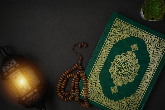 Saint Al Quran avec la signification de la calligraphie arabe écrite d'Al Quran et chapelet sur fond noir avec un espace de copie