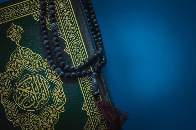 Saint Coran avec calligraphie arabe signifiant Al Quran et tasbih ou chapelet sur fond noir Mise au point sélective et espace de copie