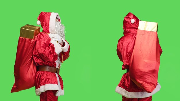 Photo saint nick attend quelque chose pour donner des cadeaux et des jouets du sac rouge, homme habillé comme le père noël pendant les vacances saisonnières. jeune adulte en costume portant un sac avec de nombreux cadeaux.