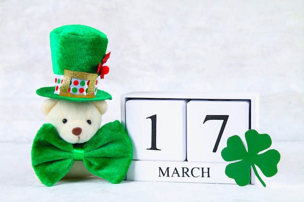 Photo saint patrick. un calendrier en bois montrant le 17 mars. chapeau vert et arc.