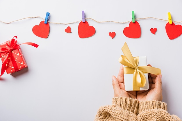 Saint Valentin et anniversaire Mains de femme tenant un cadeau ou une boîte cadeau décorée et une surprise de coeur rouge