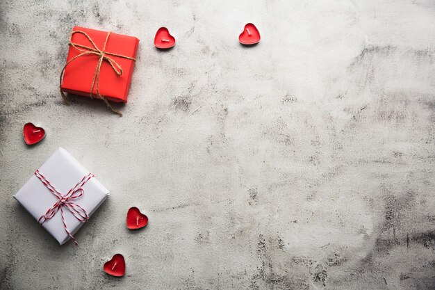 Saint-Valentin, boîte-cadeau de papier kraft avec un ruban et des bougies sur fond gris.