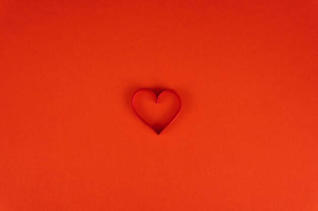 Saint Valentin ou concept d'anniversaire avec copie espace Coeur de ruban rouge sur papier rouge