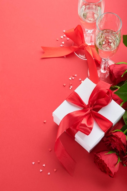 Saint Valentin ou concept de dîner romantique table romantique argenterie verres à vin coffret cadeau roses et symbole de l'amour coeur rouge sur fond rouge concept de dîner romantique Saint Valentin
