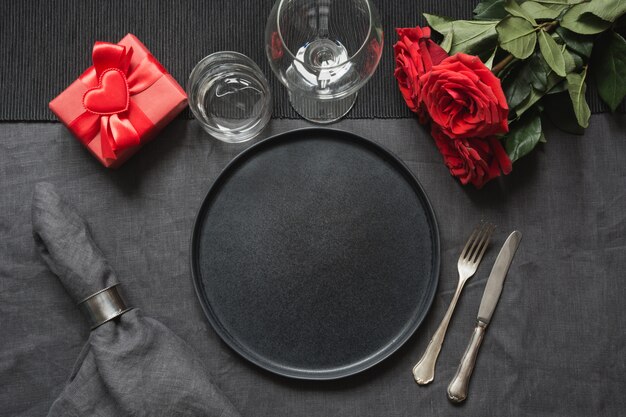 Saint Valentin Ou Dîner D'anniversaire. Cadre De Table Elegance Avec Rose Rouge Sur Une Nappe En Lin Noir.