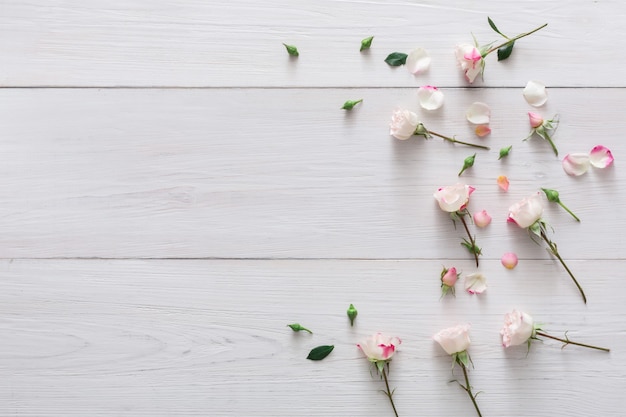 Saint-Valentin avec des fleurs et des pétales de rose rose dispersés avec espace copie sur bois rustique blanc