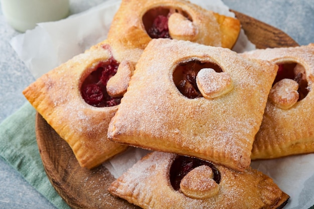 Saint Valentin en forme de coeur Tartes à la main Mini pâte feuilletée ou tartes à la main farcies de pomme et saupoudrer de sucre en poudre dans l'assiette Idée de collation romantique maison Saint Valentin Vue de dessus Espace de copie