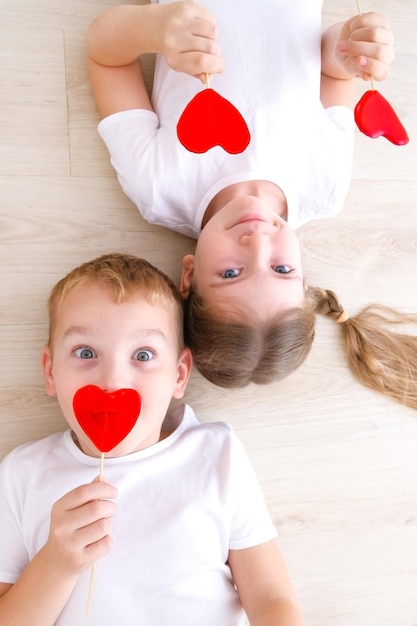 Photo saint valentin un garçon et une fille mangent des sucettes caramel rouge en forme de coeur