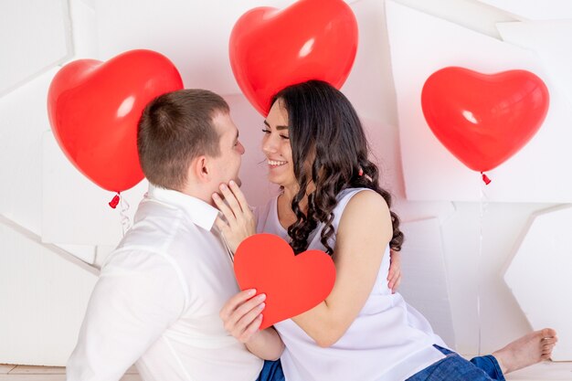 La Saint-Valentin, un mec avec une belle fille se regarde avec un regard amoureux, qui tient un grand cœur rouge