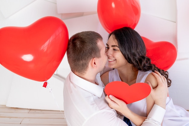 La Saint-Valentin, un mec avec une belle fille se regarde avec un regard amoureux, qui tient un grand cœur rouge