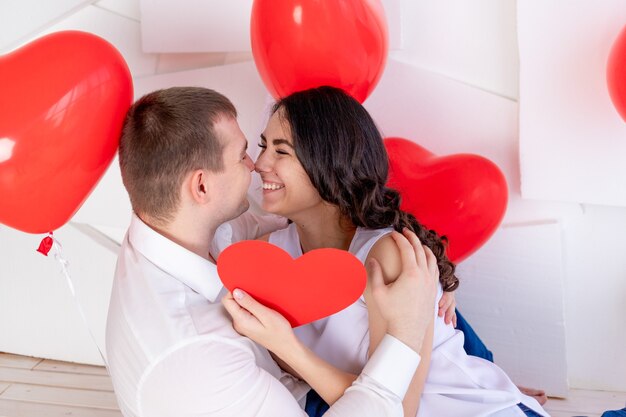 La Saint-Valentin, un mec avec une belle fille se regarde avec un regard amoureux, qui tient un grand cœur rouge