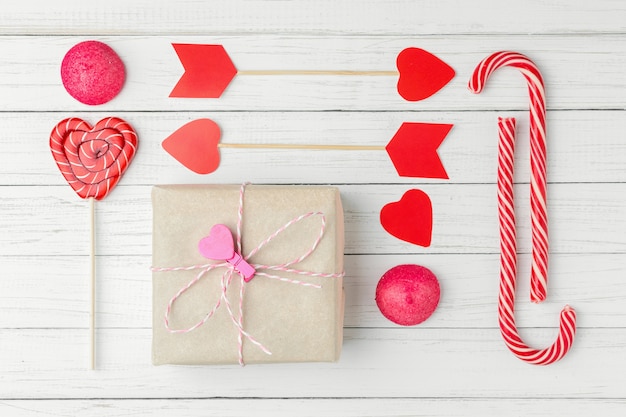 Photo saint valentin sertie de bonbons, boîte cadeau et papier coupé coeur sur bois blanc