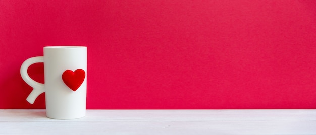 Photo saint valentin avec tasse blanche coeur café rouge sur la tasse, fond de mur rouge, espace copie et bannière pour le texte. concept de la saint-valentin.