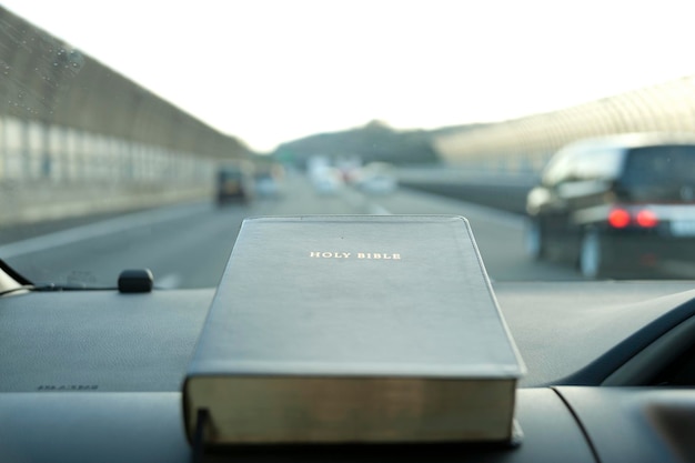 Photo sainte bible fermée à l'intérieur de la voiture arrière-plan flou autoroute avec des voitures