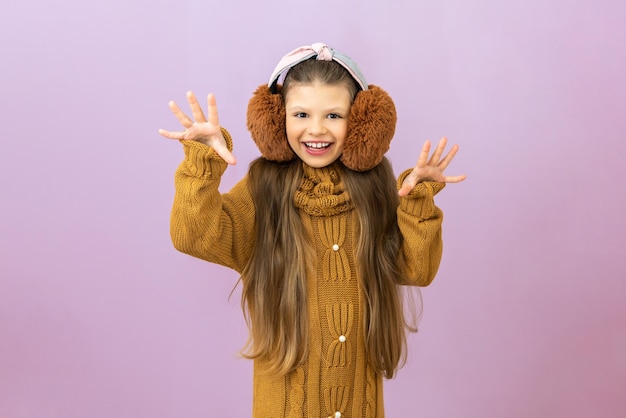 La saison froide, la fille a levé les mains et crie un pull chaud et des écouteurs en fourrure pour réchauffer l'enfant