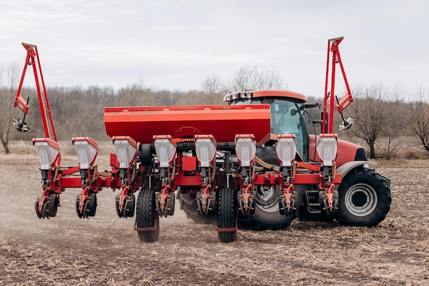 Photo saison des semis de printemps un agriculteur avec un tracteur sème des graines de maïs sur son champ planter du maïs avec un semoir traîné semis agricoles le concept d'agriculture et de machines agricoles