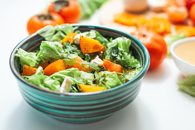 Photo salade aigre-douce légère avec mandarines au kaki et salade de vitamines d'hiver au fromage et ingrédients