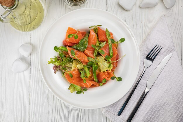 Salade d'asperges et de légumes verts sur une assiette blanche et une table blanche