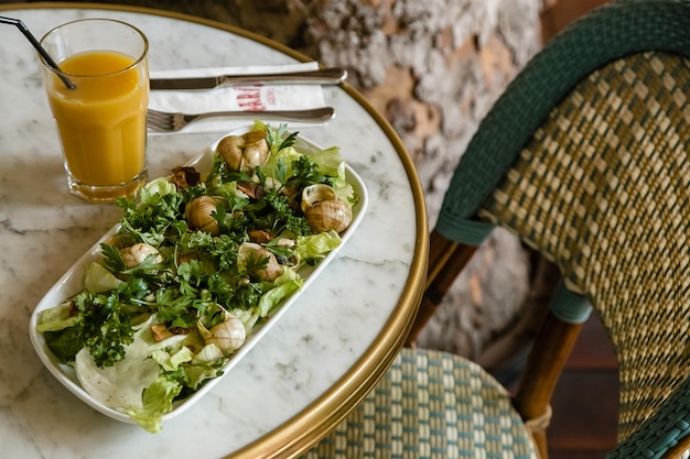 Une salade sur une assiette avec un verre de jus d'orange