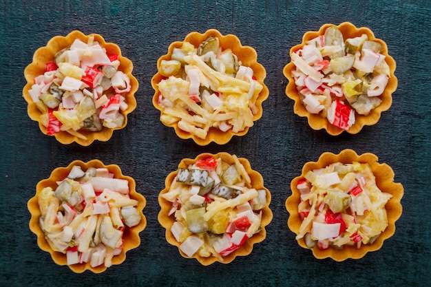 Salade au crabe en tartelettes sur fond noir.