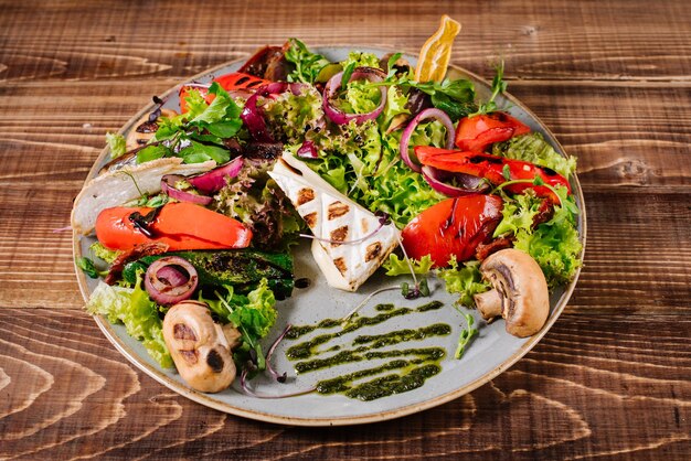 Photo salade au fromage, champignons et légumes sur fond de bois