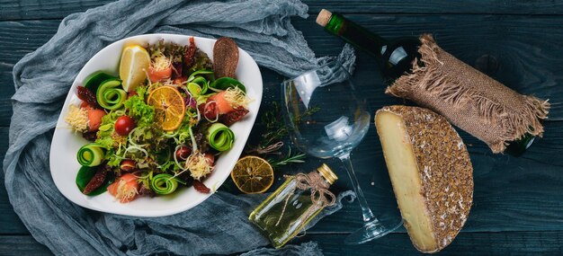 Salade au fromage de saumon salé et feuilles de salade Une bouteille de vin Sur une surface en bois Vue de dessus Espace libre pour votre texte