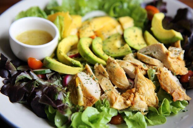 Salade au poulet avocat et mangue sur fond de bois